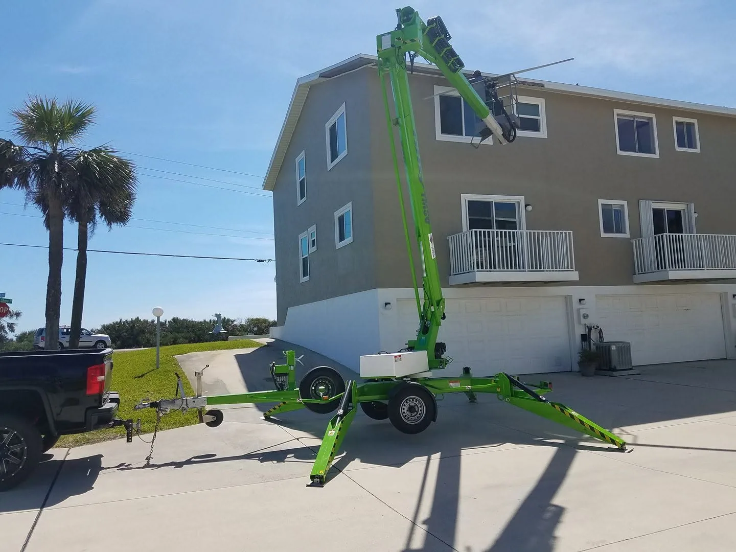 Green towable boom lift three story gray townhouse gutter work, Sanford